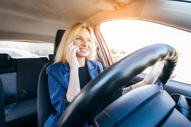 Sürücü kadın telefonda dikkati dağılmış bir şekilde araba kullanıyor ve yan tarafa bakıyor.