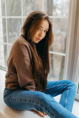 Stüdyoda poz veren kapüşonlu genç kadın. 