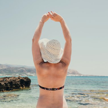 Hasır şapka kadınla sahilde güneşten korur