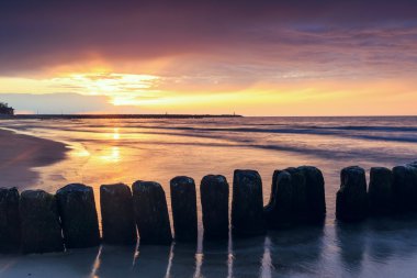 ahşap bir dalgakıran, uzun pozlama ile sahilde günbatımı