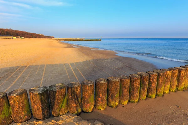 Solnedgång på stranden med en trä vågbrytare, lång exponering — Stockfoto