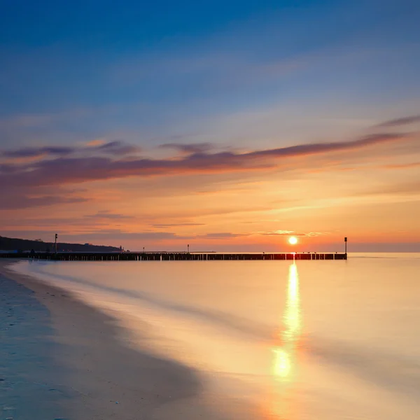 Puesta de sol en la playa con un rompeolas de madera, larga exposición — Foto de Stock