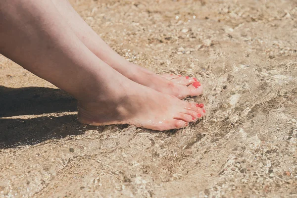 Female feet with red pedicure in beach sand, close up — Stock Photo, Image