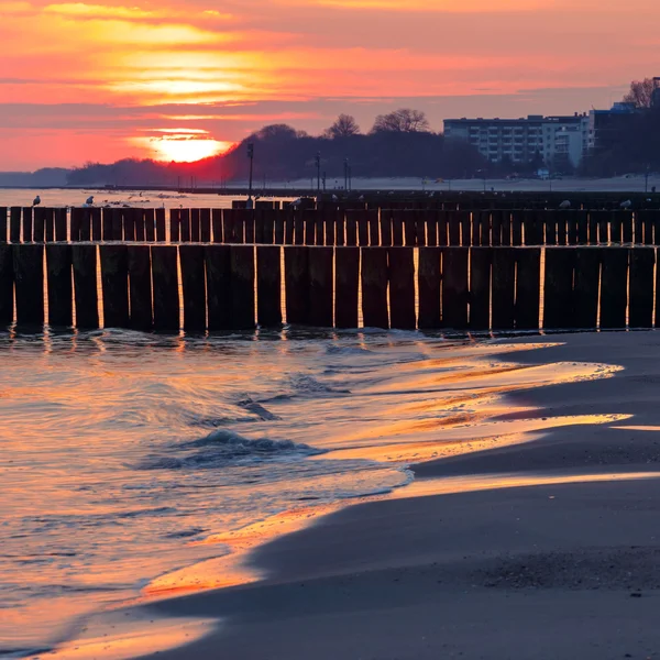 Puesta de sol en la playa con un rompeolas de madera, larga exposición — Foto de Stock