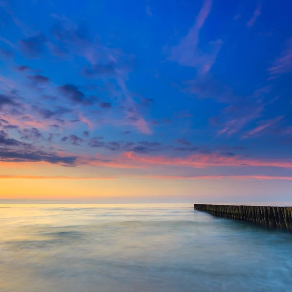 Ahşap bir dalgakıran, uzun pozlama ile sahilde günbatımı — Stok fotoğraf