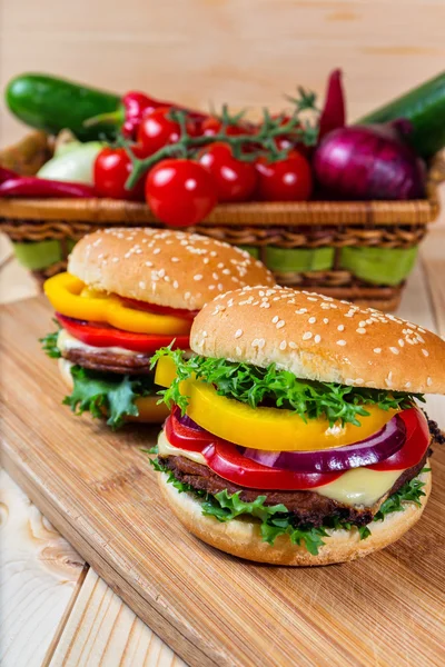 Hamburguesa casera con verduras frescas en la tabla de cortar — Foto de Stock