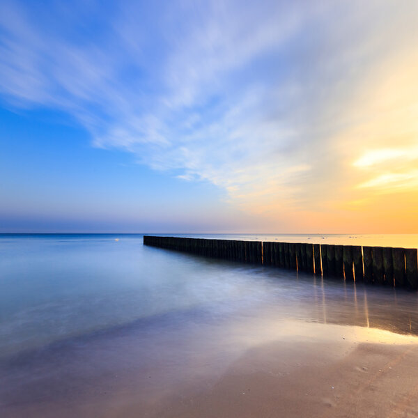 sunset on the beach with a wooden breakwater, long exposure