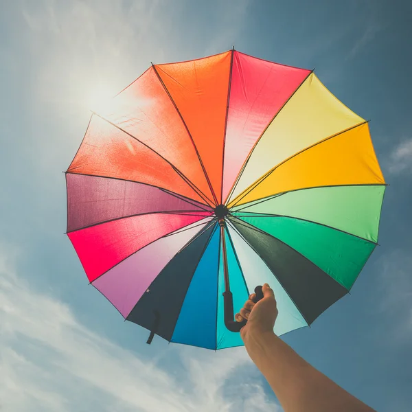 Parapluie arc-en-ciel ouvert coloré sur fond bleu ciel, look vintage — Photo