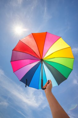 Mavi gökyüzü arka plan üzerine açık renkli gökkuşağı şemsiye