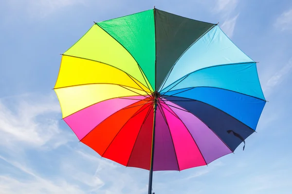 Aperto ombrello arcobaleno colorato su sfondo cielo blu — Foto Stock