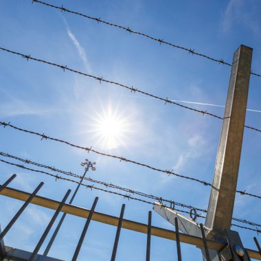 dikenli tel ve mavi gökyüzü arka plan üzerinde güneş