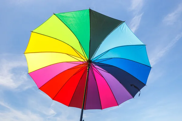 Aperto ombrello arcobaleno colorato su sfondo cielo blu — Foto Stock