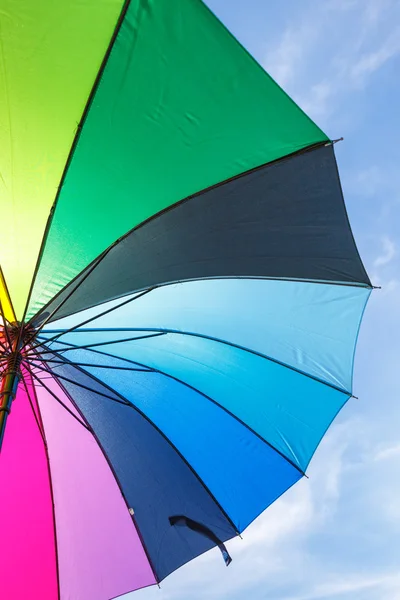 Aperto ombrello arcobaleno colorato su sfondo cielo blu — Foto Stock