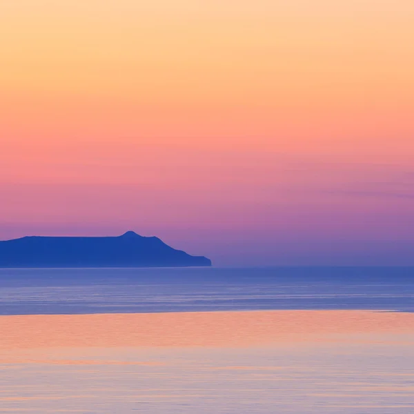 Закат над горой с отражением на море — стоковое фото