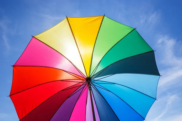 Aperto ombrello arcobaleno colorato su sfondo cielo blu — Foto Stock