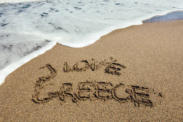 Słowo kocham Grecji napisane w piasku na plaży — Zdjęcie stockowe