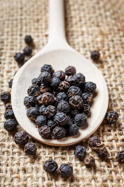 Black pepper on the wooden spoon — Stock Photo, Image