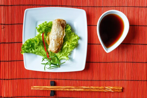 Fried spring rolls on red bamboo mat — Stock Photo, Image