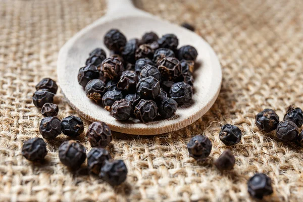 Black pepper on the wooden spoon — Stock Photo, Image