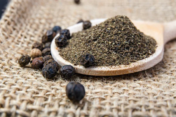 Black pepper on the wooden spoon — Stock Photo, Image