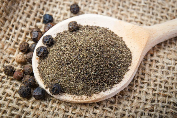 Black pepper on the wooden spoon — Stock Photo, Image