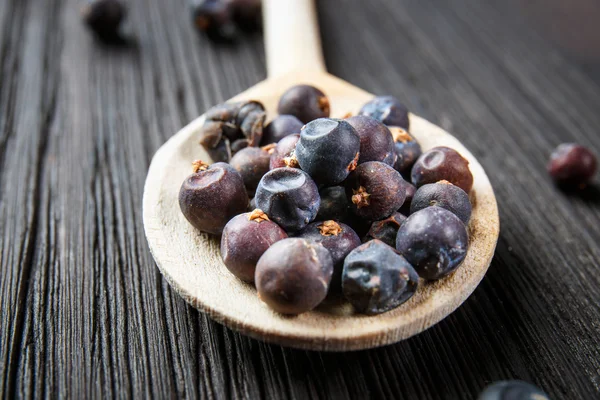 Juniper berries on old wooden spoon — Stock Photo, Image