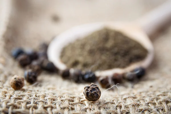 Black pepper on the wooden spoon — Stock Photo, Image