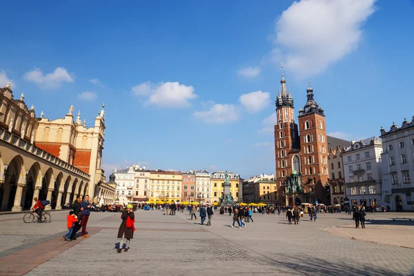 KRAKOW, PUOLA - 07 maaliskuu 2015: Tunnistamattomat turistit vierailevat päätorilla Pyhän Marian basilikan edessä Krakovassa, Puolassa 07 maaliskuu 2015. Krakovan vanhakaupunki Unescon perintökohteeksi — kuvapankkivalokuva