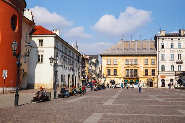 KRAKOW, POLONIA - 07 de marzo de 2015: Turistas no identificados visitan la pequeña plaza del mercado en Cracovia, Polonia, el 07 de marzo de 2015. Casco antiguo de Cracovia declarado patrimonio de la Unesco — Foto de Stock