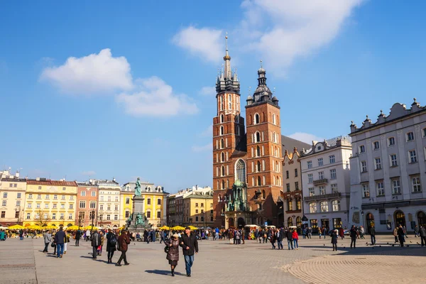KRAKOW, POLONIA - 07 de marzo de 2015: Turistas no identificados visitan la plaza principal del mercado frente a la Basílica de Santa María, en Cracovia, Polonia, el 07 de marzo de 2015. Casco antiguo de Cracovia declarado patrimonio de la Unesco —  Fotos de Stock