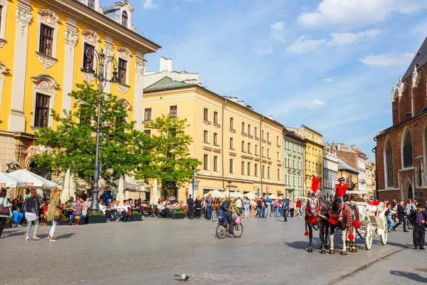 KRAKOW, POLONIA - 15 de mayo de 2015: Turistas no identificados visitan la plaza principal del mercado en Cracovia, Polonia — Foto de Stock