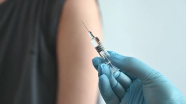 Doktor erkek hastalara iğne yapıyor. Doktorların elinde şırıngalar var..