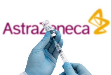 Seul, Güney Kore-Aralık 2020: COVID-19 Aşı Konsepti. Şırınga ve şişeyi tutan tıbbi personelin elleri, arka planda AstraZeneca Şirketi logosu..