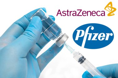 Seul, Güney Kore-Aralık 2020: COVID-19 Aşı Konsepti. Arka planda şırınga ve şişe, AstraZeneca ve Pfizer şirket logosu tutan tıbbi personelin elleri.