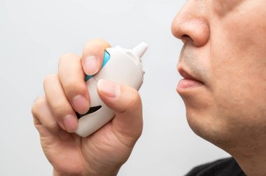 Burun spreyi kullanan olgun bir adamın yakın çekimi..