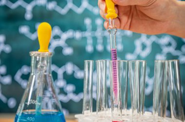 Tahta arka planı ve çeşitli kimyasal formülleri olan laboratuvar camları..