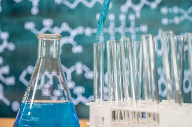 Tahta arka planı ve çeşitli kimyasal formülleri olan laboratuvar camları..