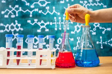 Tahta arka planı ve çeşitli kimyasal formülleri olan laboratuvar camları..