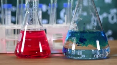 Tahta arka planı ve çeşitli kimyasal formülleri olan laboratuvar camları..