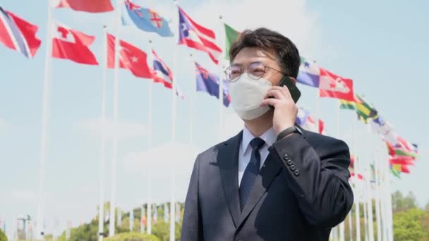 Asiatischer Geschäftsmann Mittleren Alters Mit Maske Und Smartphone Unter Verschiedenen — Stockvideo