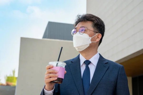 Midaldrende Asiatisk Forretningsmand Byen Iført Maske Holder Kaffekop - Stock-foto