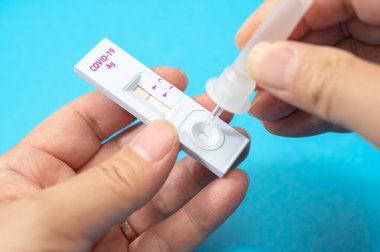 Coronavirus testi için COVID-19 ev antijen kiti kullanan adamların elleri..
