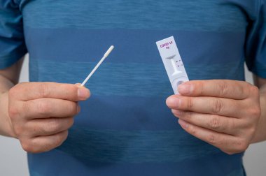 Coronavirus testi için COVID-19 ev antijen kiti kullanan adamların elleri..