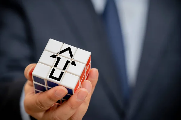 Handen van een zakenman die een kubus met een pijl pictogram zichtbaar houdt. — Stockfoto