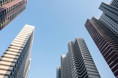 Düşük açılı bakış açısı modern yüksek katlı ofis binalarına ve gökdelenlere açık mavi gökyüzüne bakıyor.