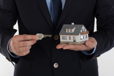 Bir anahtar veren ve yazlık elinde tutan işadamı.