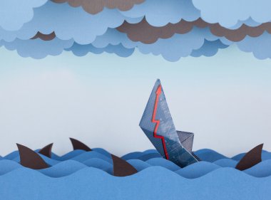 Paper boat is sinking into paper sea.  clipart