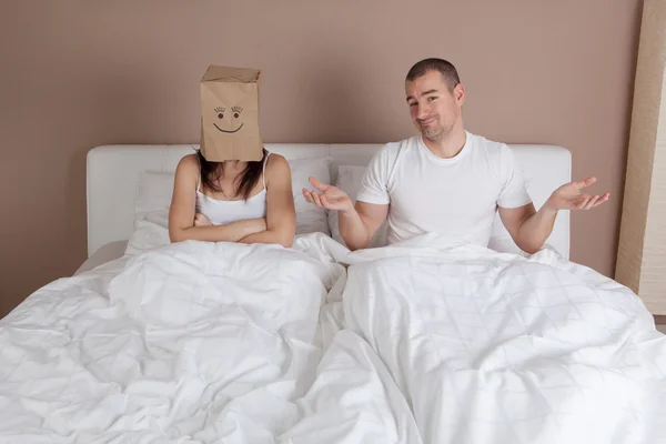 Funny situation in bed. Woman with paper bag over head — Stock Photo, Image