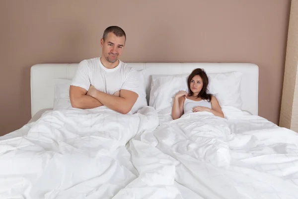 Mladý pár leží v posteli a žena je velmi malý, ale self potvrzení — Stock fotografie
