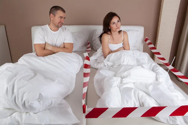 Mujer joven enojada acostada separada de su marido en la cama —  Fotos de Stock